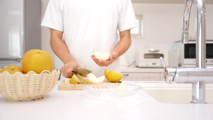 Asian man cutting pears in the kitchen