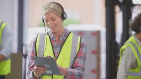 Female manager wearing headset in distribution warehouse whilst using digital tablet - shot in slow motion - Powered by Shutterstock - Get 15% off with code: PIKWIZARD15