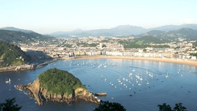 High angle view of the La Concha Bay, with boats docked in the middle of the bay. In front plan is Santa Clara Island, in background, the city of San Sebastian. Static video