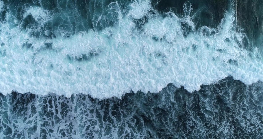 Aerial top down view deep blue ocean waves crashing and foaming on the shore. 4K | Shutterstock HD Video #1094263573