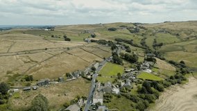 Aerial footage of a industrial rural village with old mill and chimney stack surrounded by fields. Shot at Leeming above Oxenhope and adjacent to Leeming Reservoir. Shot in West Yorkshire England.