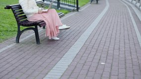 unrecognizable female in white coat pink skirt sit bench use laptop talk webcam having interview meeting. freelance worker working outdoors in city park concept distance technology internet video call