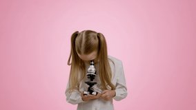 Interesting science. Curious little girl looking in microscope, playing like scientist or doctor, enjoying experiment result, pink studio background, slow motion - Powered by Shutterstock - Get 15% off with code: PIKWIZARD15