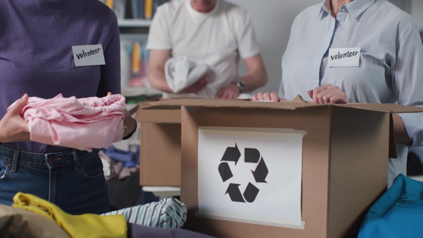 Close up of people pack clothes in cardboard box for recycling. Eco-friendly organization sort clothes to recycle Royalty-Free Stock Footage #1094275247