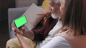 Mature happy couple communicates online call. A gray-haired husband and wife are talking to relatives on the phone. Video call on smartphone. Remote communication. Green screen to paste