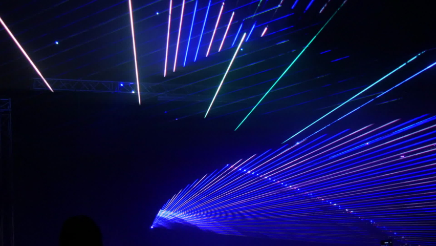 Light laser show on a black background of the night sky, outdoor performance. Multi-colored laser beams turn into various shapes, projection on smoke. Information Technology Conference