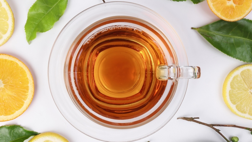 different types of fresh raw green tea leaf flower bud lemon orange slice transparent glass teacup saucer liquid tea on white background top view pan zoom rotate  Royalty-Free Stock Footage #1094278905