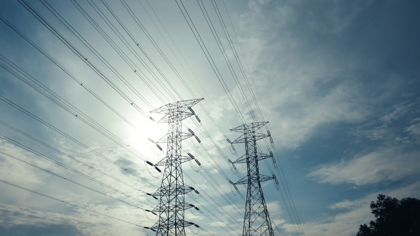A zoom in timelapse footage with noise effect electic transmission tower with moving cloud and sun insight. Electric and energy concept.