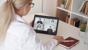 Online education. Business courses. Video lesson. Unrecognizable woman having virtual meeting with students on tablet computer in light room interior.