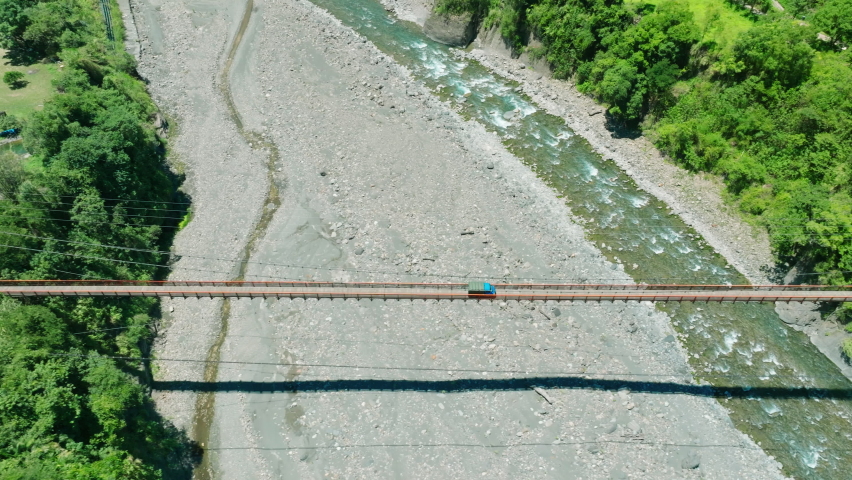 Aerial view of road and small  hanging bridge over  mountain river 