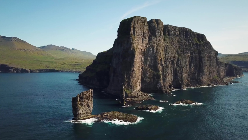 Aerial view of a Rock formation Risin og Kellingin in Faroe Islands. The giant and the witch from Iceland who tried to steal the Faroe Islands. Sunny day in summer. High quality 4k footage. Royalty-Free Stock Footage #1094304339