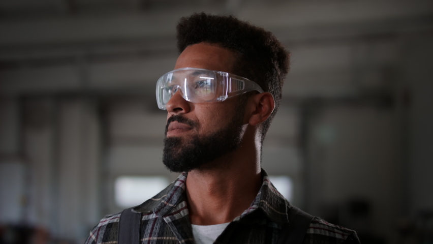 Potrait of young heavy industry worker wearing safety glasses, smiling.