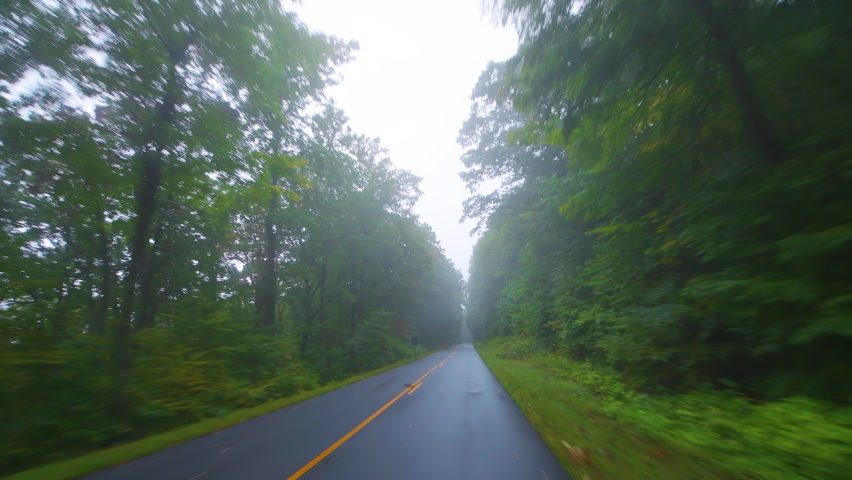 Point of view pov vehicle car driving at Blue Ridge Parkway, Virginia during autumn foliage Appalachian mountains national park forest dark mist fog moody weather on empty road