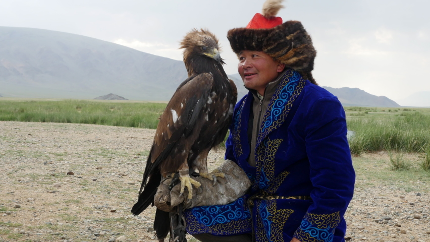 Kazakh Eagle Hunter in traditional clothing holding a golden eagle on his arm near Bayan-Olgii in West Mongolia.