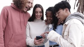 Multiracial group of young friends having fun using social media app on mobile phone. High quality 4k footage