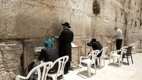 A few individual Jews are praying at the Western Wall site on midday. they are taken from behind and therefore unrecognizable. an NTSC video clip, old city of Jerusalem, Israel.
