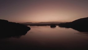 beautiful shot of sunrise on the edge of the lake with hills in the background. dawn arrives with a purple sky. 4K videos.