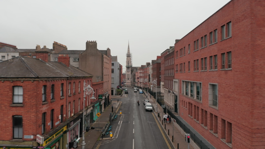 Forwards fly through street surrounded by brick houses. Revealing Abbey Presbyterian Church and rooftop view of district. Dublin, Ireland