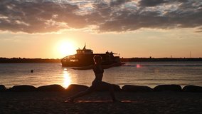 Slow motion video of a woman doing yoga workout on Baltic sea coastline during sunset