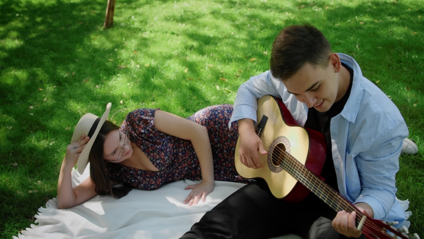 A man plays guitar next to his girlfriend