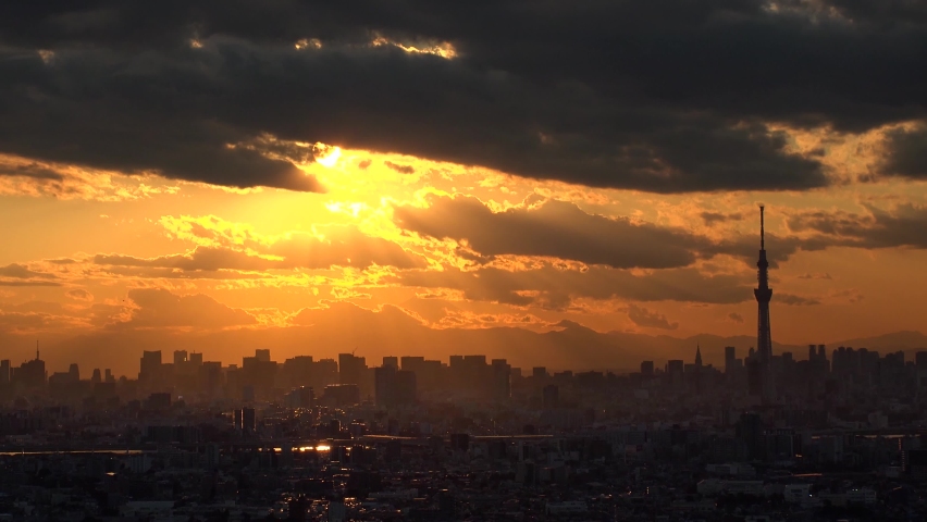 TOKYO, JAPAN : Aerial high angle sunset CITYSCAPE of TOKYO and MOUNT FUJI. View of sinking sun and buildings at downtown area. Japanese city life and nature concept. Time lapse shot, dusk to night. Royalty-Free Stock Footage #1094320383