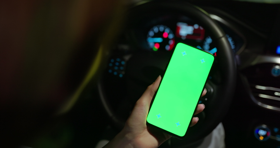 Asian female driver is sitting in the car and watching her smartphone with green screen at night Royalty-Free Stock Footage #1094321753