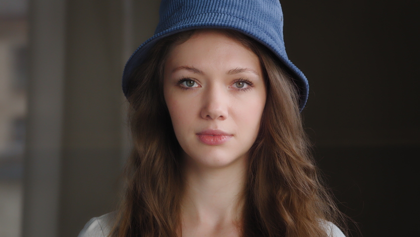 Female portrait close-up young attractive pretty caucasian woman looks at camera poses indoors confused worried shy mischievous girl feels guilty embarrassed pulls hat over eyes hiding under headdress Royalty-Free Stock Footage #1094330761