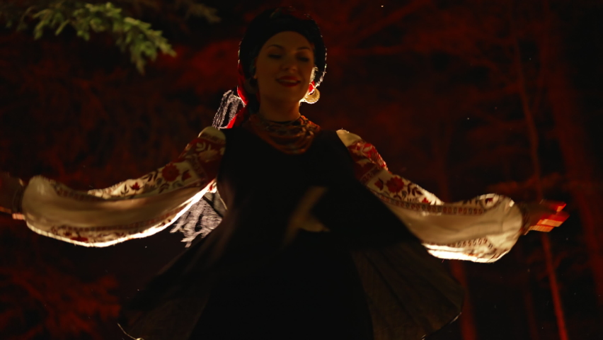 Dancing woman in traditional ukrainian handkerchief and costume on dark night forest background. Lady in vintage national dress - vyshyvanka, ancient coral beads. Concept of ethnic style.