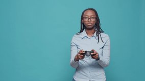 African american woman playing video games with controller, using tv console to have fun with gameplay and online gaming competition. Holding joystick to play action games on camera.