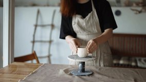 Girl potter forms her product and turns the potter's wheel