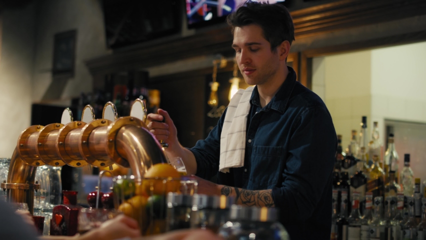 Busy male bartender beer at bar to the clients. Shot with RED helium camera in 8K.  Royalty-Free Stock Footage #1094338897
