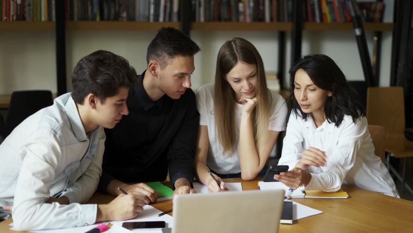 Group of students, high school pupils gather in college library, discuss topics, work together on creative task, prepare for university test or exams use laptop. Education, study, modern tech concept Royalty-Free Stock Footage #1094340867