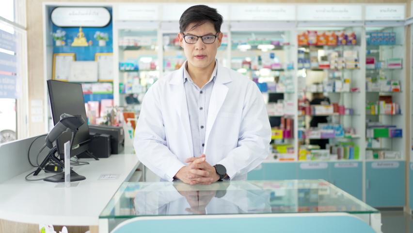 Portrait of Handsome Asian man professional pharmacist ready for medication advice about health, medicine, drugs and supplements in modern drugstore. Medical pharmacy and healthcare providers concept.