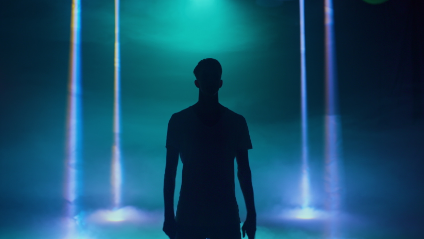 Male dancer performing in the night club. Contemporary, hip-hop, house dance. Silhouette of a dancer in a blue neon light lamps on a black background. High quality 4k footage