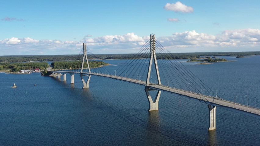 An aerial video of The Replot Bridge filmed on a sunny day. The drone is circulating around the bridge when cars are driving on it. The bridge leads to Replot and Kvarken Archipelago World Heritage
