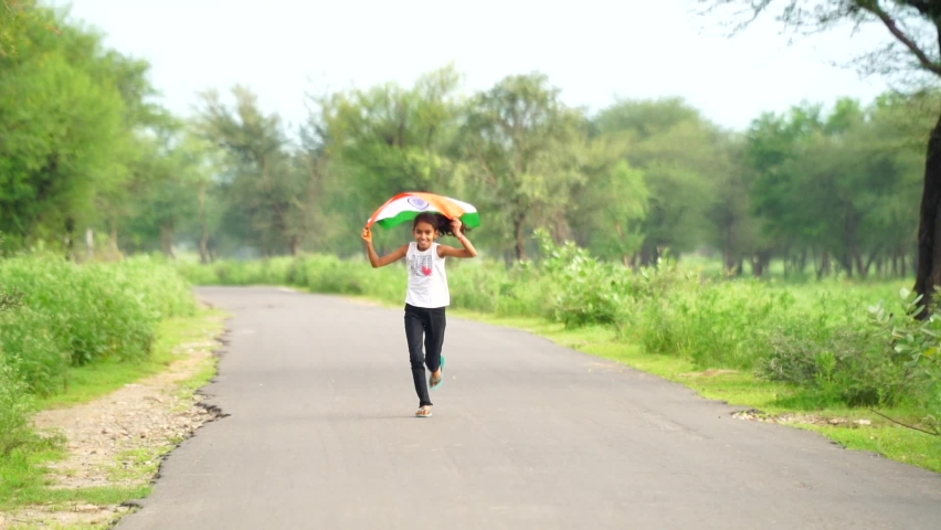 Cute little indian kids holding, waving or running with Tricolour with greenery in the background, celebrating Independence or Republic day