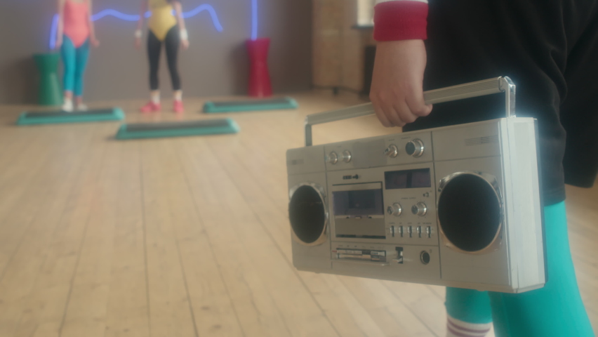 Low section of cropped man bringing tape recorder to fitness studio at daytime, starting group step aerobics class Royalty-Free Stock Footage #1094350373
