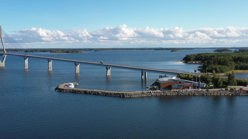 A cinematic drone reveal shot of a bridge called Replot Bridge, the longest Bridge in Finland. The weather is sunny and the sky as well as the sea is blue. 