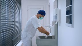 In the modern hospital in operation room in front of the camera doctor surgeon before start the surgery washing hands very well and wearing medical uniform and protective mask - Powered by Shutterstock - Get 15% off with code: PIKWIZARD15