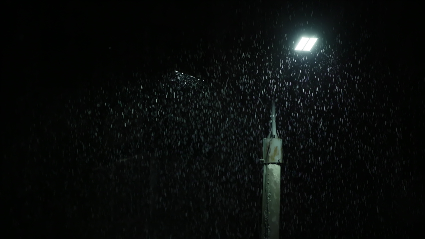 Double led panel lamppost under heavy rain at night. Midsize view of raindrops against a lamppost bright light. Static viewpoint. long raindrop tails | Shutterstock HD Video #1094357551