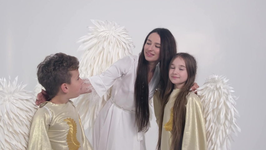 Magic video, family dressed in angel costumes, they dance on a white background 
