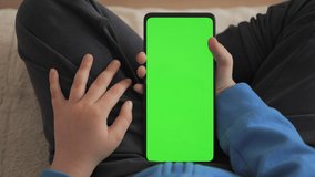 Point of View of Child at Living Room Using Phone With Green Mock-up. Phone With Green Mock-up Screen Chroma Key Surfing Internet Watching Content Videos Blogs Learning. Little Boy Playing Video Games