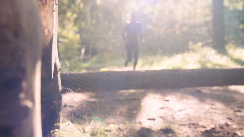 Athlete Woman Runs Forwards and Jumps Over the Log in the Morning Forest. Slow Motion Panning Shot