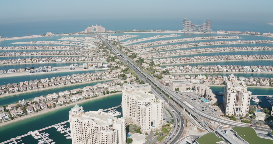 Stunning aerial view of Dubai's Palm Jumeirah in the UAE. 4K Drone footage revealing blue seas and The Palm on a sunny day. The metro tram visible down the center of the palm with blue gulf sea.