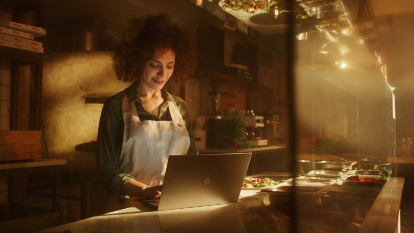 In Restaurant: Beautiful Female Chef Using Laptop Computer. Authentic Italian Pizzeria With Delicious Organic Eco Food. Bi-racial Female Entrepreneur Working in Her Small Business Family Shop Royalty-Free Stock Footage #1094381831