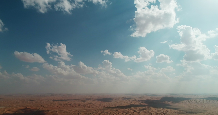 Beautiful aerial view over the UAE desert showing the vast expanse of sand dunes and endless emptiness. Tranquil blue skies and clouds scattered across the gulf.