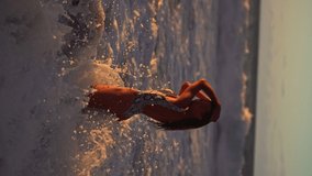 Vertical video Young athletic woman in swimsuit at sunset, ocean.
