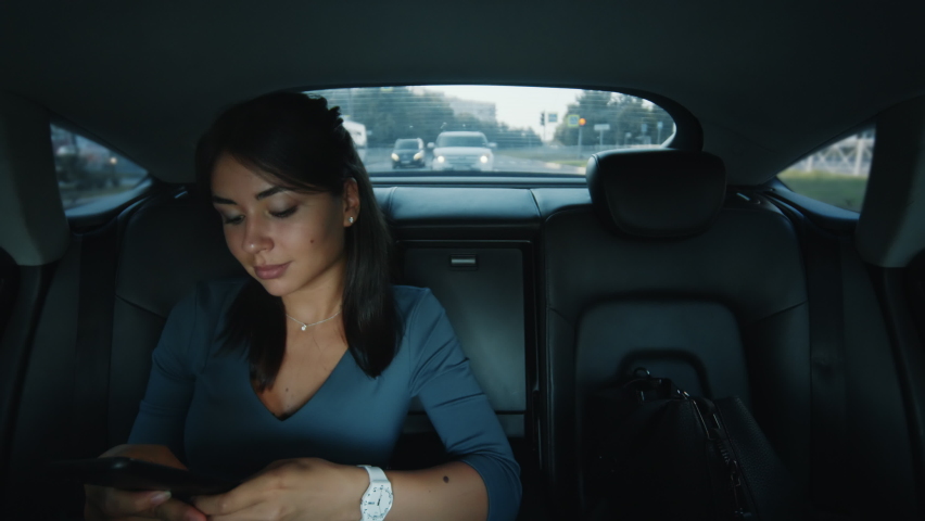 Young beautiful business woman sitting in the back seat of a car, recording a voice message, smiling. Slow motion 4k footage Royalty-Free Stock Footage #1094384617