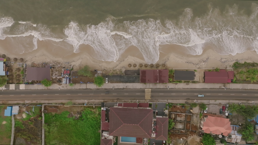 Top down aerial footage of a road and beach and ocean waves just outside of Freetown, Sierra Leone.