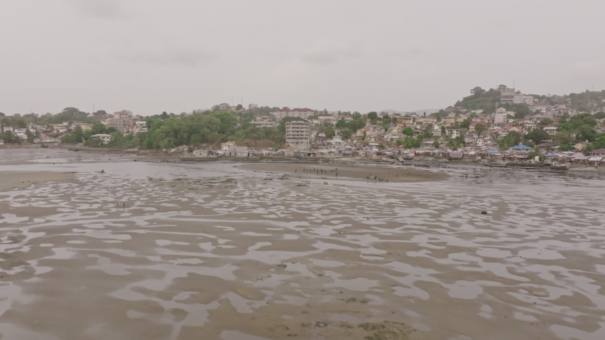People in Freetown, Sierra Leone playing soccer on a patch of land in low tide.